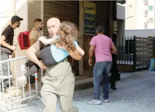  ?? — Reuters ?? A man carrying a girl runs after gunfire erupted in Beirut on Thursday.