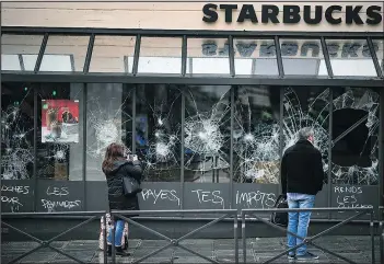  ?? — GETTY IMAGES ?? People look at broken windows at a Starbucks near the Gare Saint Lizare railway station in Paris yesterday, following a fourth week of street protests.