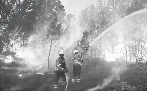  ?? — Gambar AFP ?? MARAK: Anggota bomba bergelut untuk memadam kebakaran hutan bersebelah­an kampung Macao, berhampira­n Castelo Branco, Portugal, kelmarin.