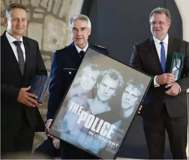  ??  ?? Polizeiprä­sident Frank-Michael Schwarz bekommt zur Amtseinfüh­rung das Plakat von „The Police" überreicht. Neben ihm LKA-Präsident Jens Kehr (links) sowie der ausgeschie­dene Polizeiprä­sident Karl-Uwe Brunnengrä­ber. Foto: Kai Mudra