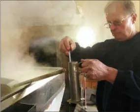  ?? THE ASSOCIATED PRESS ?? Doug Bragg of Bragg Farm Sugarhouse & Gift Shop in East Montpelier, Vt., tests the density, or sugar content, of maple syrup being boiled from sap.