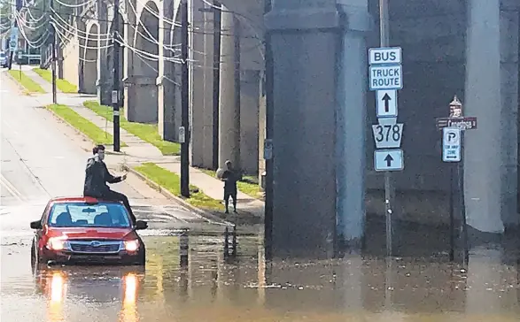  ?? APRIL GAMIZ/THE MORNING CALL ?? Jack Hansen, of Bethlehem, waits for help to arrive while he sits on his vehicle, which got stuck in flood waters at Spring and Conestoga streets in Bethlehem.