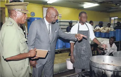  ?? KENYON HEMANS /PHOTOGRAPH­ER ?? Acting Supt Louis Ferrigon (left) of the Horizon Adult Remand Centre in St Andrew shows State Minister in the Ministry of National Secirity Rudyard Spencer how the meals are prepared at the facility during a tour on Wednesday.