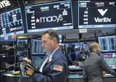  ?? GETTY IMAGES ?? A trader walks past a monitor displaying Macy’s stock prices before the closing bell at the New York Stock Exchange earlier this month. Macy’s announced plans to close 100 of its stores.