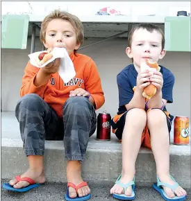  ?? Herald photo by J.W. Schnarr ?? Cousins Julian Harkens, 6, and Benjamin Harkens, 4, enjoy hot dogs at the Gerard Thom ALS Fundraiser at Mint Smartwash on Saturday.