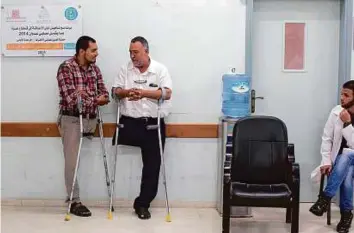  ?? AFP ?? Emad Al Firi (centre), who was wounded during the 50-day war between Israel and Hamas in 2014, talking to a fellow amputee at Gaza’s Artificial Limbs and Polio Centre.