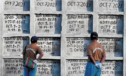  ?? — AFP ?? Grim farewell: Prison inmates looking at tombs during a mass burial of 70 unclaimed bodies of prisoners at New bilibid Prison cemetery in muntinlupa, metro manila.