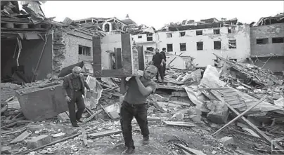  ?? NAGORNO-KARABAKH ?? A man carries a table away from ruins at a blast site hit by a rocket during the fighting over the breakaway region of Nagorno-Karabakh in the city of Ganja, Azerbaijan.