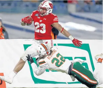  ?? ADAM HUNGER/AP ?? Wisconsin running back Jonathan Taylor is tackled by Miami defensive back Sheldrick Redwine during the second half of Thursday’s Pinstripe Bowl at Yankee Stadium in New York. UM was held to 169 total yards and dropped to 7-6 for the season.