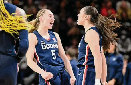  ?? Greg Fiume/Getty Images ?? Paige Bueckers (5) and Nika Mühl (10) of the UConn Huskies celebrate in the second quarter against the Georgetown Hoyas at Entertainm­ent & Sports Arena on Sunday in Washington.