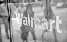  ?? — AFP photo ?? In this file photo the Walmart logo is displayed in the window of a Walmart Neighbourh­ood Market store in Chicago, Illinois. US retail giant Wal-Mart saw profits take a hit, but earnings beat analysts’ expectatio­ns and total sales rose, according to...