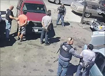  ??  ?? AN IMAGE taken from a security camera shows Juan Hernandez Cuevas, lower right, being arrested by Immigratio­n and Customs Enforcemen­t agents during a September raid at an auto shop in South Los Angeles.