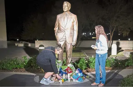  ?? — AFP ?? Farewell to a legend: Mourners placing candles at the foot of a statue of Bush outside the George Bush Presidenti­al Library in College Station, Texas.