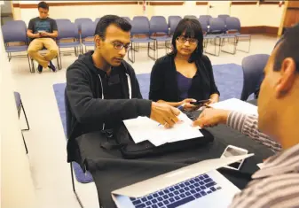  ?? Leah Millis / The Chronicle ?? Omar Masry (right) of San Francisco’s Office of Short-Term Rental helps Mehul Dhorda (left) and wife Arpita Patel register as short-term rental hosts during a workshop held in June.