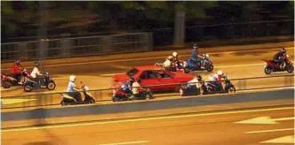  ??  ?? Nocturnal nuisance: Filepic of motorcycli­sts riding dangerousl­y and intimidati­ng a lone car driver along Jalan Semantan in Kuala Lumpur at night.