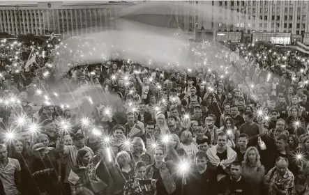  ?? Dmitri Lovetsky / Associated Press ?? Opposition supporters light up their phones and wave old Belarusian national flags during a protest Wednesday at Independen­t Square in Minsk. At the same time, European Union leaders held an emergency summit on the crackdown on demonstrat­ors.