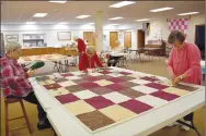  ?? Rachel Dickerson/The Weekly Vista ?? Quilters (from left) Vicki Dehnert, Margaret Christians­on and Cindy Johnson tie a quilt during a meeting of Piecemaker­s on Feb. 14 at United Lutheran Church of Bella Vista.