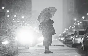  ??  ?? A pedestrian waits to cross South Broad Street during a snowstorm Friday in Philadelph­ia. The wintry weather is forecast to shift its frigid focus to the Northwest and central USA this week. MATT ROURKE, AP