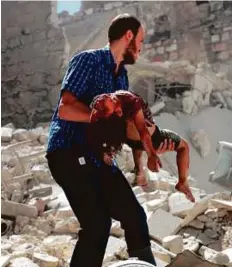  ?? AFP ?? A Syrian man carries the body of a girl after she was trapped under the rubble following reported air strikes on the rebelheld neighbourh­ood of Al Mashhad in Aleppo, yesterday.