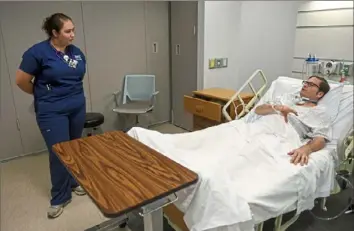  ?? Steve Mellon/Post-Gazette ?? Jordan Goss, a senior nursing student at Robert Morris University, listens to a critique from Andy Allen, an actor hired to play the role of man injured in a motorcycle accident. Medical and nursing programs use profession­al actors to simulate various situations students will encounter once they enter the workforce.