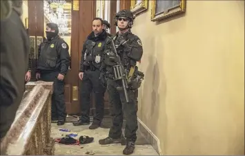  ?? Victor J. Blue / Washington Post News Service ?? U.S. Capitol police officers stand near blood on the floor after demonstrat­ors Wednesday breached barricades to the Capitol and stormed the building.