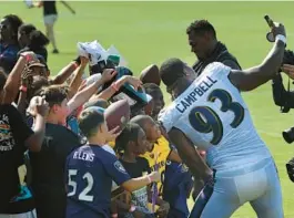  ?? KENNETH K. LAM/BALTIMORE SUN ?? Ravens defensive lineman Calais Campbell, right, takes a selfie with young fans after a training camp practice. When the pads came on Monday, the defense came to play.