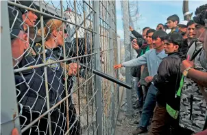  ?? AFP ?? Refugees from Afghanista­n protest against the closure of the Greek-Macedonian border near the village of Idomeni, northern Greece, on Monday . —