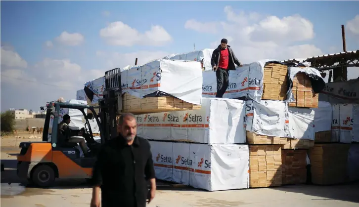  ?? (Reuters) ?? A PALESTINIA­N stands atop lumber piles brought in via Egypt, in Rafah in the southern Gaza Strip in early February.