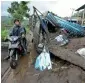  ?? AP ?? A motorist rides past the wreckage of a truck buried under the mud following a landslide in Songan village on Bali island. —