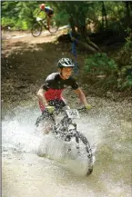  ??  ?? Nick Hancock, a category 3 racer from Russellvil­le, fords a creek July 16 during cross-country races on the final day of the 19th annual Fat Tire Festival at Lake Leatherwoo­d City Park in Eureka Springs.