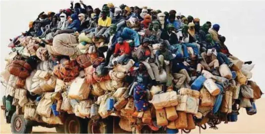  ??  ?? Migrants in an overloaded truck
