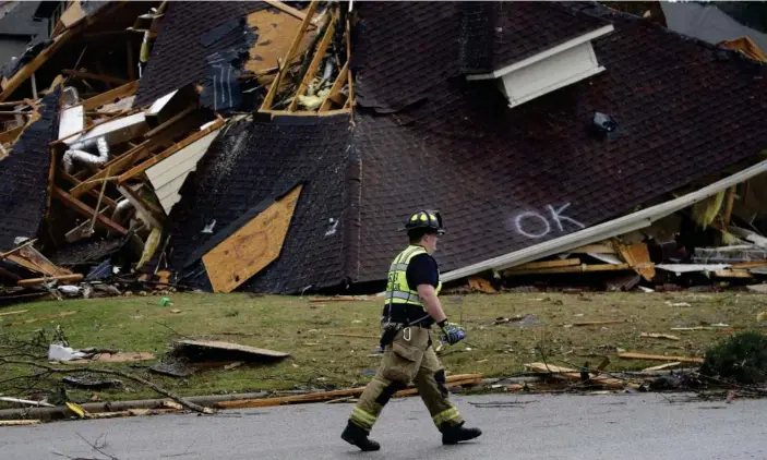  ?? Photograph: Butch Dill/AP ?? A firefighte­r surveyed damage to a house after a tornado touched down south of Birmingham, Alabama, on Thursday.