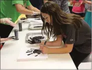  ?? Kristina Wilder / Rome News-Tribune ?? Pepperell student Maggie Bagwell signs her handprint.