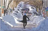  ?? CHARLES KRUPA/THE ASSOCIATED PRESS ?? Mollie Lane carries a shovel full of snow down the street to a pile while digging her car out in the South Boston neighborho­od Friday.