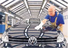  ?? JENS MEYER/ASSOCIATED PRESS ?? An autoworker checks a Golf VII car during a press tour at the Volkswagen plant in Zwickau, Germany, in 2012. Volkswagen employs thousands of American workers in Tennessee.