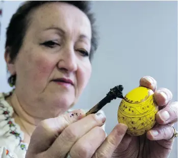  ?? STEVE BOSCH/PNG STAFF ?? Oksana Szulhan of North Vancouver applies a design with beeswax using a traditiona­l pen-like tool called a kitska to create another beautiful Easter egg. More of her intricate work is seen above.