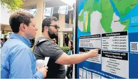  ?? STAFF PHOTO BY KIMBERLI DIMARE ?? Gregory Mertz, left, 28, of Boca Raton, listens as Florida Atlantic University student Jesse Rubizovsky, 21, of Coral Springs, explains the regional map of Israel and the Arab world during an event celebratin­g Israel’s 65th anniversar­y.