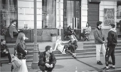  ?? EMILIO MORENATTI/AP PHOTOS ?? As normalcy slowly returns after the Russian retreat, people gather and talk outside a terrace bar last week in central Kyiv.