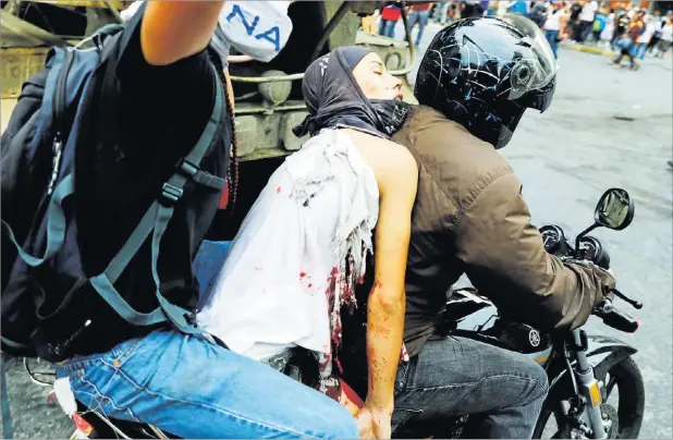  ??  ?? Un manifestan­te herido es trasladado en moto al hospital durante una protesta de la oposición venezolana contra el Gobierno de Nicolás Maduro.