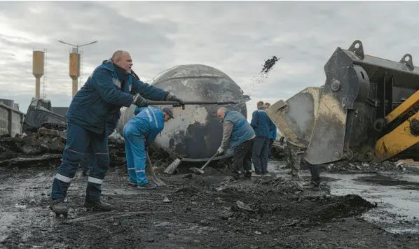  ?? ANDREW KRAVCHENKO/AP ?? Workers on Oct. 27 clean up a fuel depot hit by a Russian missile in the town of Kalynivka, about 18 miles southwest of Kyiv, Ukraine.