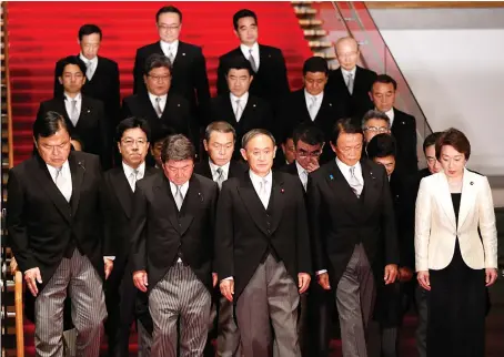  ?? AP ?? Japan’s Prime Minister Yoshihide Suga, center, with cabinet ministers this week. Suga’s plans for structural reforms will focus more on spurring competitio­n, rather than deeper social change.