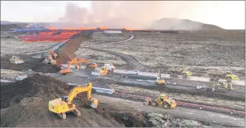  ?? ?? Aerial view shows emergency personnel using diggers to build a protective wall trying to prevent flowing lava to reach the centre of drindavik.