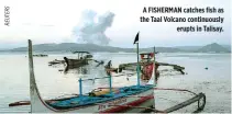  ??  ?? A FISHERMAN catches fish as the Taal Volcano continuous­ly erupts in Talisay.