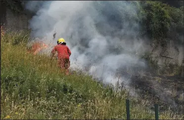  ?? Photo by Michelle Cooper Galvin ?? Firefighte­rs battle a blaze that threatened to engulf a parched grassy area at the back of Lackabane Village near Killarney on Monday.