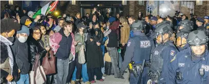  ?? (Photo by Alex Kent/AFP via Getty Images) ?? NYPD OFFICERS face protesters after detaining demonstrat­ors and clearing an encampment set up by pro-Palestinia­n students and activists at the New York University campus on Monday.