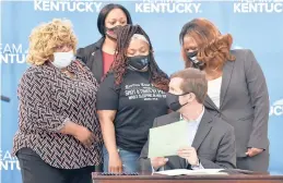  ?? TIMOTHY D. EASLEY/AP ?? Kentucky Gov. Andy Beshear signs a partial ban on no-knock warrants as Tamika Palmer, the mother of Breonna Taylor, back row center, and others watch.