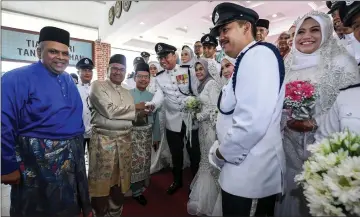  ??  ?? Mohamad Fuzi (second left) congratula­tes newly weds at the mass wedding reception organised by PDRM with the cooperatio­n of Bank Muamalat at Pulapol. — Bernama photo