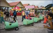  ?? NANCY BOROWICK / NEW YORK TIMES ?? Children are pulled on a barrel train through a market in Hagatna, Guam, in late June. North Korea has threatened to create an “enveloping fire” around the U.S. territory and military outpost.