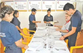  ??  ?? El instructor Juan Mancuello observa mientras los estudiante­s practican en la presentaci­ón de una mesa de hotel o restaurant­e.