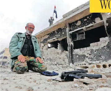  ?? LOUAI BESHARA / AFP / GETTY IMAGES ?? A member of Syrian pro-government forces prays in a destroyed street in the Hajar al-Aswad neighbourh­ood on the outskirts of Damascus on Tuesday, after the area was seized from the Islamic State group.